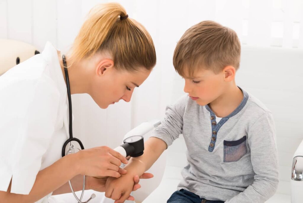 specialist in dermatologie pediatrica examineaza pielea unui baietel cu suspiciune de alergii